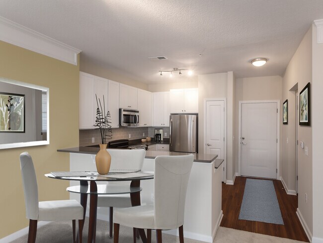 Dining area and kitchen with quartz stone countertop, white cabinetry, tile backsplash, stainless steel appliances and hard surface flooring - Avalon Arlington North Apartments