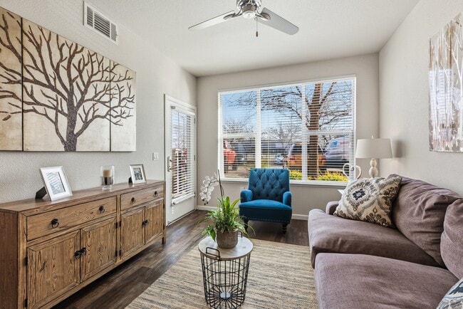Aspire Apartments Tracy CA A living room with a blue chair and a painting of a tree on the wall.
