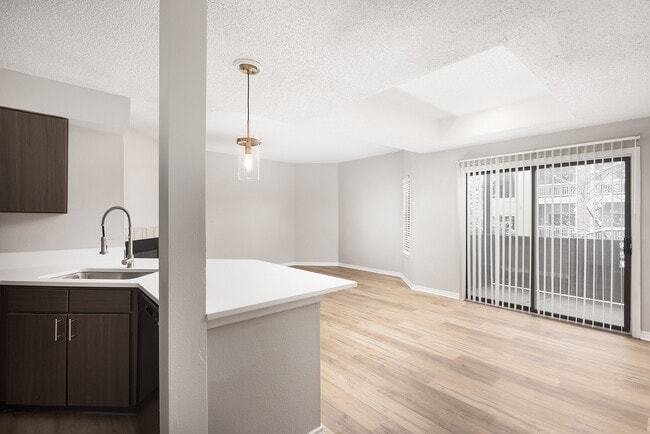 Cocina moderna en un apartamento con elegantes encimeras blancas, electrodomésticos de acero inoxidable y cálidos suelos de madera. - Avana Belmar