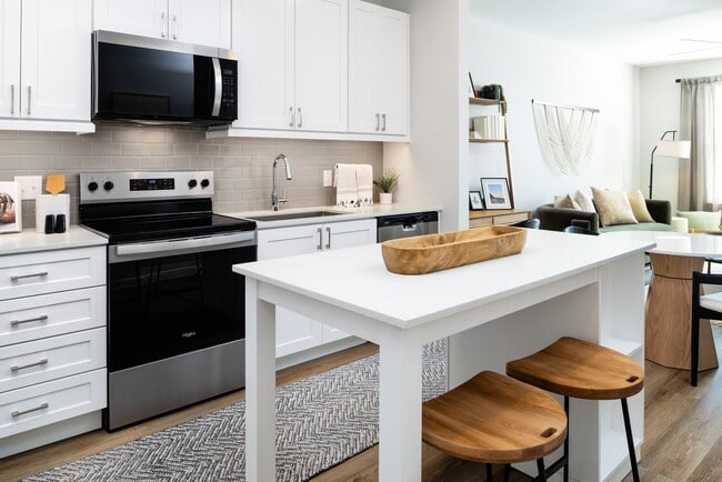 Finish Package I kitchen with stainless steel appliances, white cabinetry, grey tile backsplash, white quartz countertops, and hard surface flooring