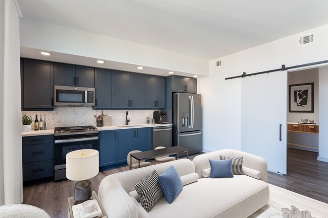 Studio Living Area and Kitchen featuring blue cabinets and marble-style backsplash and countertops.