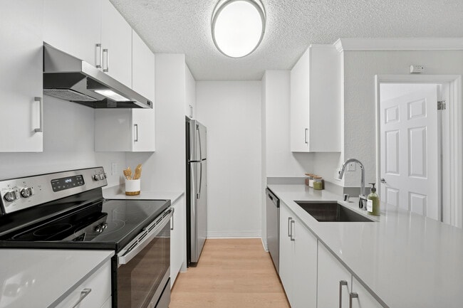 Renovated Package I kitchen with white cabinetry, grey quartz countertops, and hard surface flooring