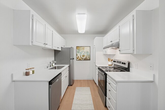 Renovated Package I kitchen with stainless steel appliances, white cabinetry, white quartz countertops, and hard surface flooring