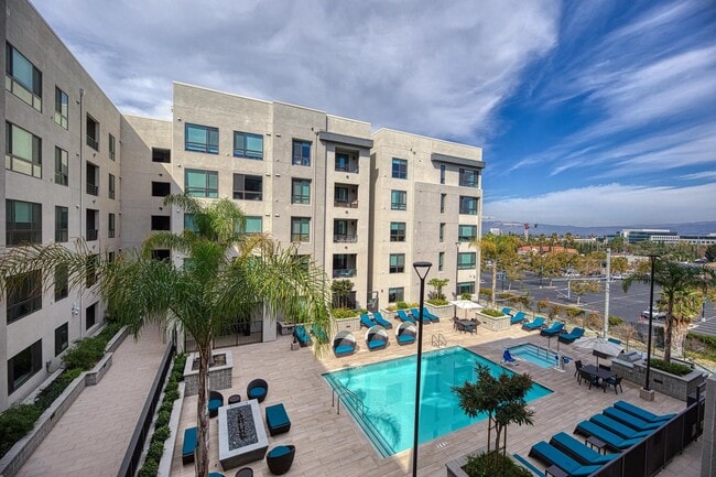 Expansive pool terrace with seating, palm trees, and a firetable that enhances the outdoor experience.
