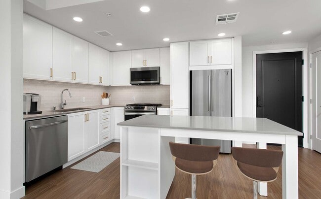 Building A Upgrade Design 1 kitchen with quartz countertops, stainless steel appliances, backsplash and island