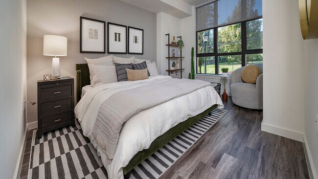 Spacious apartment bedroom with wood-style flooring.