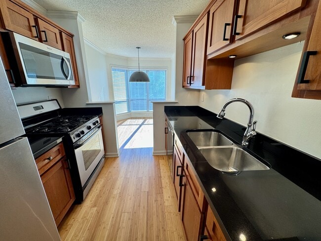 kitchen with cherry cabinets, granite counters, stainless/black appliances, dining room at end - 209 14th St. NE #119 Unit 209 14th St. NE #119