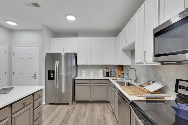 Elegant modern kitchen showcasing sleek stainless steel appliances, pristine white cabinetry, and stylish wood flooring, perfect for culinary creativity.