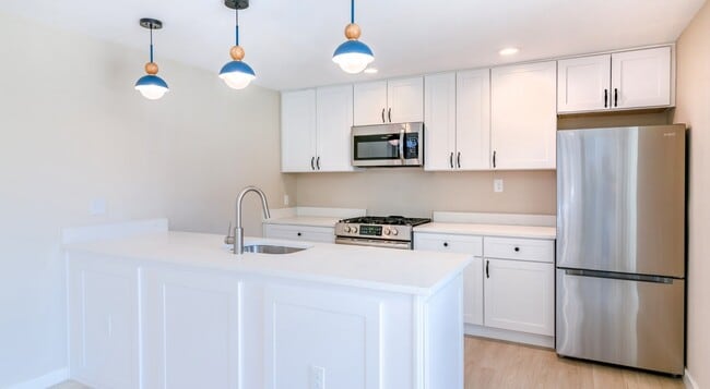 Elevate your lifestyle at Lakeshore Preserve, where this modern kitchen features sleek white cabinetry, stylish pendant lights, and top-of-the-line appliances. Ready to make this culinary dream a reality? Schedule your tour today! - Lakeshore Preserve
