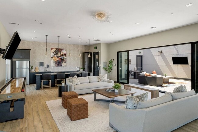 Step into the inviting lounge area at Flats on Archer, where modern design meets comfort. Natural light floods the space, creating a warm atmosphere perfect for socializing or relaxation. Explore your new lifestyle today! - Flats on Archer