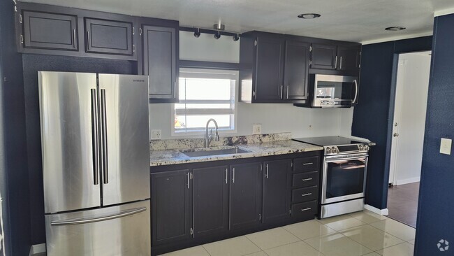 Kitchen with stainless steel refrigerator, electric stove, and microwave. - 7905 Harwell St Rental