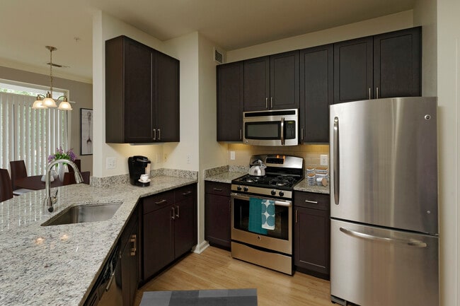 Renovated Package III kitchen with espresso cabinetry, granite countertops, stainless steel appliances, tile backsplash and hard surface flooring