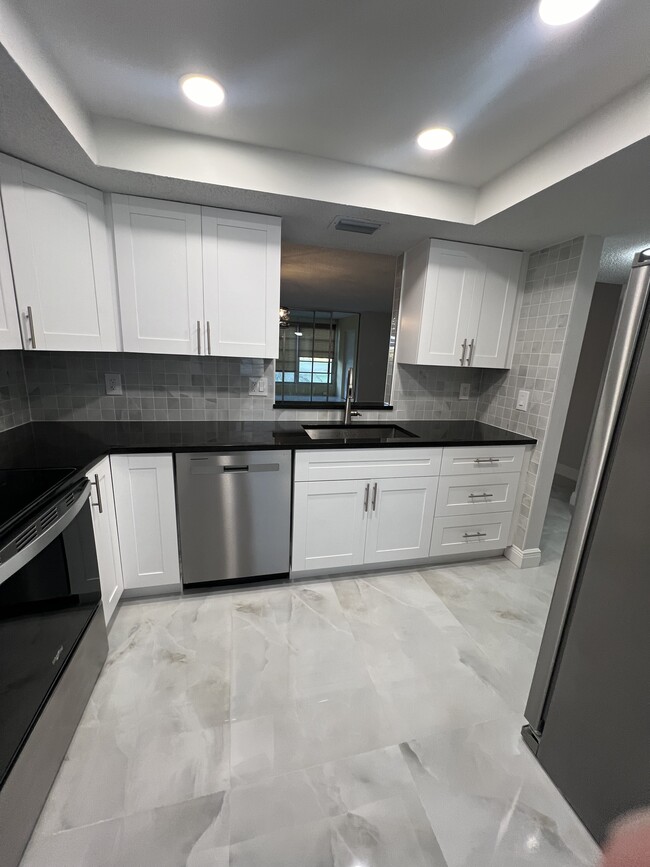 White shaker cabinets, new stainless steel appliances, and granite countertops - 1060 NW 80th Ave Condo Unit 205