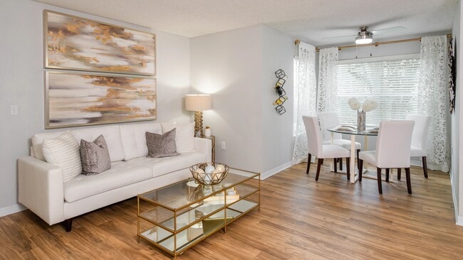 Bright, open-concept living and dining area featuring wood-style flooring and plenty of natural light—perfect for entertaining or relaxing. - Ashton Chase