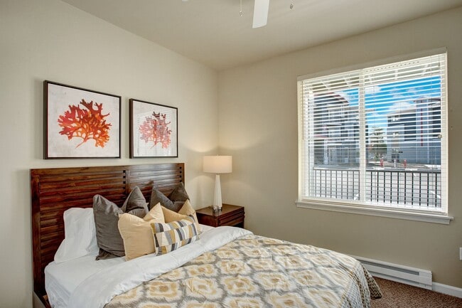 A bedroom with a large window looking out to the patio and the rest of the property with a bed, nightstand, and ceiling fan - Solara