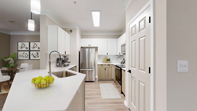 Bright kitchen with two toned cabinets with breakfast bar and view of dining room - Waterstone at Big Creek Apartments