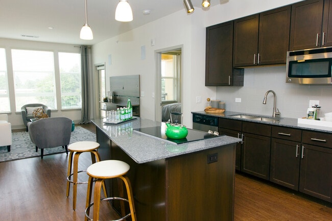 Classic Package kitchen with espresso cabinetry, speckled granite countertops, grey subway tile backsplash, stainless steel appliances, and hard surface flooring