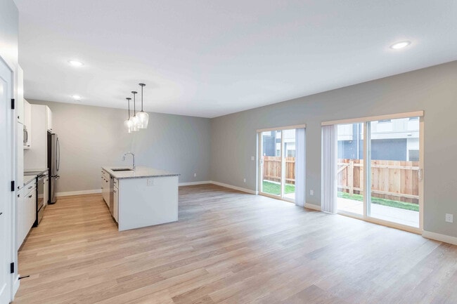 Bright and airy kitchen with granite island, modern fixtures, and expansive sliding glass doors leading to a private patio.