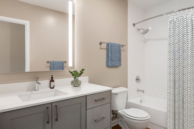Signature Collection bath with grey cabinetry, white marbled quartz countertops, and hard surface flooring