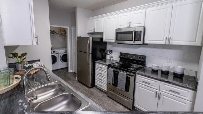 Experience timeless elegance in our updated kitchens, featuring white cabinetry, a modern subway tile backsplash, and wood-style flooring with stainless-steel appliances.