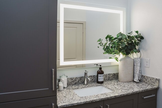 Designer bathrooms with granite countertops and backlit mirrors