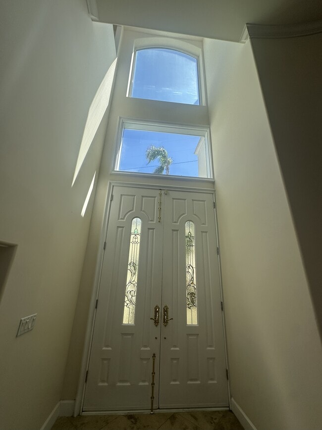 Grand double-door entry with decorative glass panels, soaring windows, and transom detail - 8120 Billowvista Dr