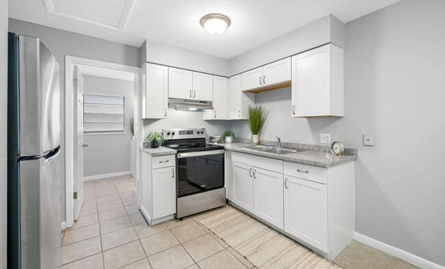 Modern kitchen with sleek stainless steel appliances, elegant white cabinetry, and stylish granite countertops. - Sunny Point Apartments