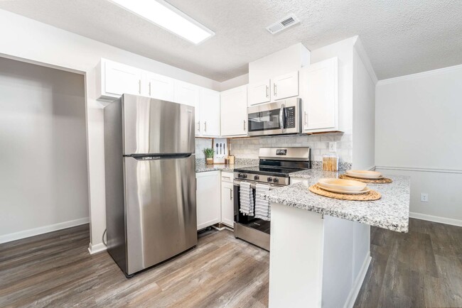 Stylish apartment kitchen at Sugar Creek Apartments in Winston-Salem, NC featuring granite countertops, stainless steel appliances, updated cabinetry, and open-concept living space.