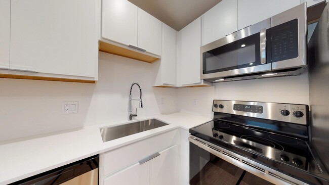 Kitchen with Stainless Steel Appliances, Farmhouse Sink, & Designer Cabinetry - Flamingo Apartments