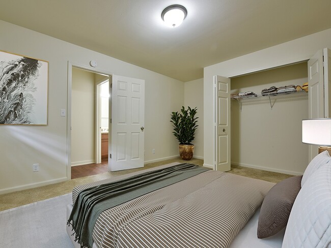 A bedroom with a closet and large window with blinds.
