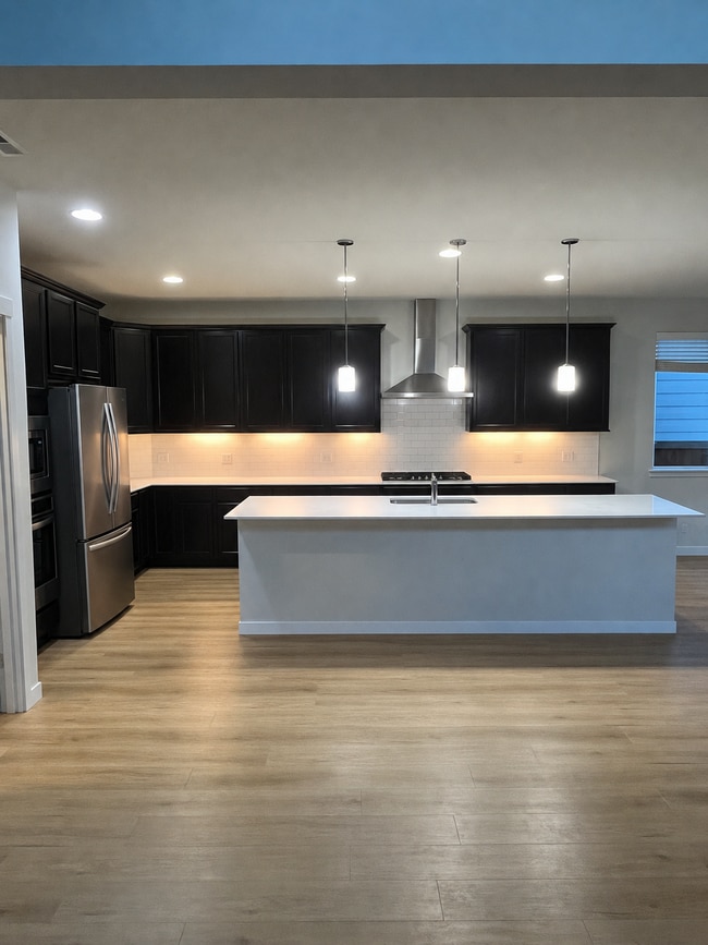 Kitchen featuring smart oven, microwave, refrigerator, gas stove, and island with quartz countertop - 8002 116th Street Ct SW
