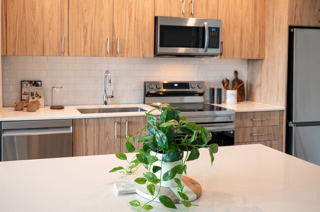 Kitchen with oak cabinetry, stainless-steel appliances, hard-surface flooring and granite countertops - Avalon Westminster Promenade