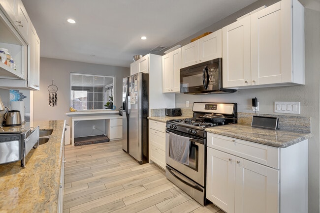 Light-filled kitchen with granite countertops, stainless steel appliances, and white cabinetry - 6136 N 9th St