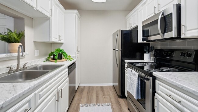 Enjoy a stylish kitchen featuring white cabinetry, stainless steel appliances, and marble-style countertops.