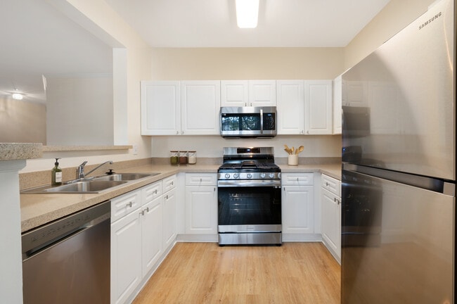 Classic Package II kitchen with white cabinetry, beige laminate countertops, stainless steel appliances, and hard surface flooring