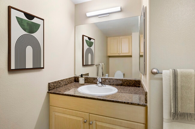 Renovated Package I bath with brown speckled granite, oak cabinetry, and hard surface flooring