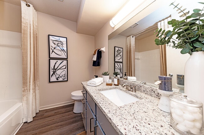 Bright bathroom with granite counters, modern cabinetry, and large mirror