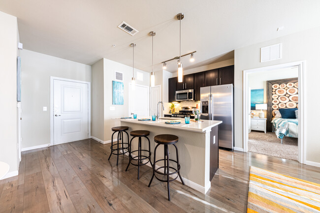 Cocinas con gabinetes oscuros, encimeras de cuarzo blanco, salpicadero de azulejos blancos tipo metro, electrodomésticos de acero inoxidable y pisos de superficie dura. - Avalon Wolf Ranch Apartamentos