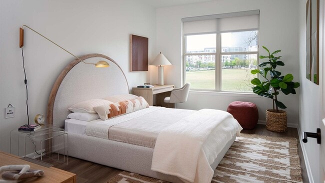 Spacious apartment bedroom with wood-style flooring. - Griffis at The Domain