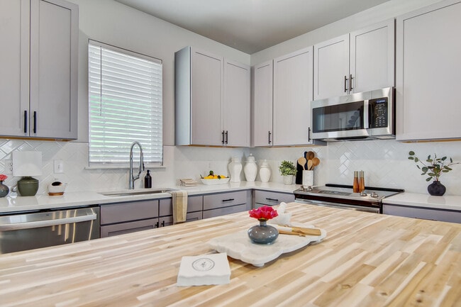 Contemporary kitchen with large island, farmhouse sink, stainless steel dishwasher, and subway tile backsplash