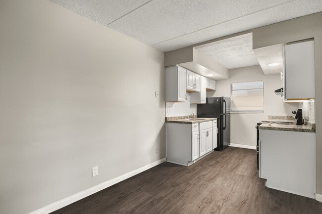 Contemporary kitchen with sleek white cabinets, modern appliances, and elegant countertop, set against stylish wood flooring. - Alderman Park Apartments