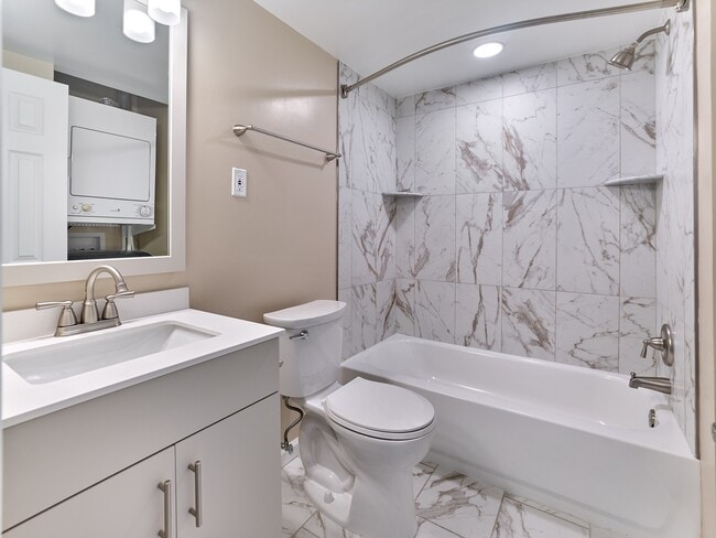 Updated bathroom with marble-style tile surround, modern fixtures, and sleek vanity in this 2 Bed,1 Bath, 908 sq. ft. home.