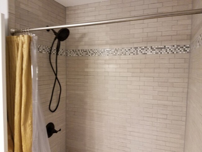 Bath/shower in this recently remodeled bathroom includes tile backsplash up to the ceiling and brand new tub. - 1809 Stark Drive