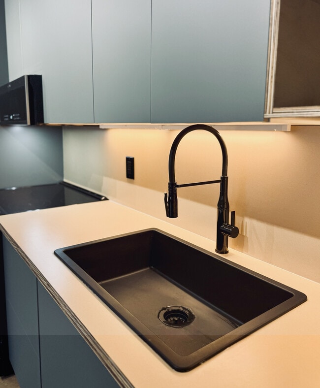 New! 2BD, 1BA - 800SF Premium Plus Available 4/6! Sleek modern kitchen with elegant black sink and stylish cabinetry, creating a contemporary ambiance.