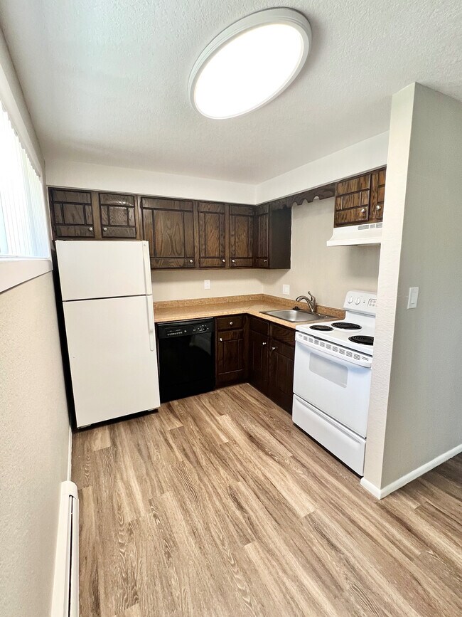 Charming kitchen with sleek wooden cabinets, modern appliances, and elegant wood flooring for a cozy culinary experience.