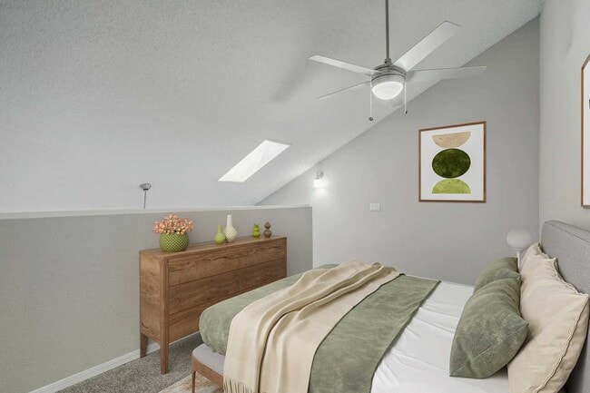 Bedroom with vaulted ceiling, skylight, ceiling fan, wood dresser, green accent bedding, and framed wall art