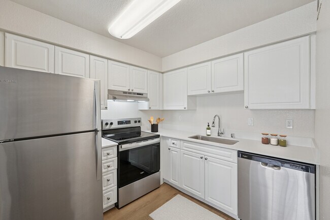 Renovated Package I kitchen with stainless steel appliances, white cabinetry, quartz countertops, and hard surface flooring