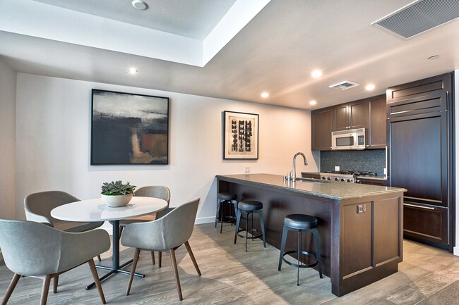 City Home kitchen featuring granite countertops and espresso cabinetry - The Bravern Apartments