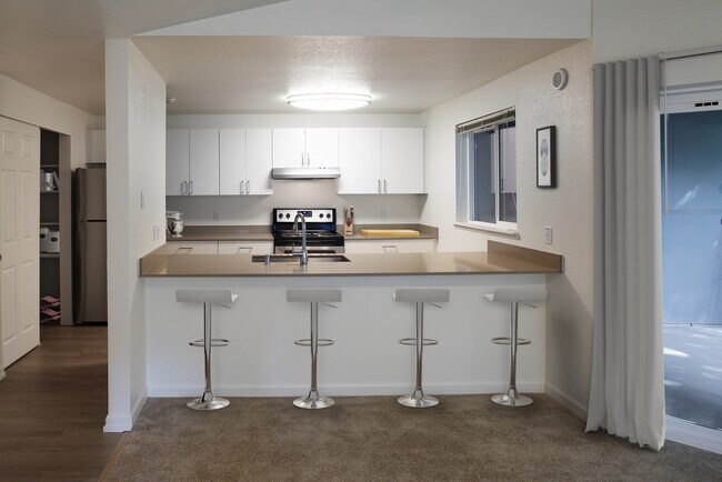 Renovated Package I kitchen with stainless steel appliances, white cabinetry, and grey quartz countertops