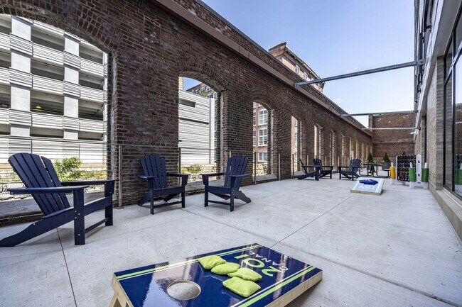 Canal-Side Courtyard With Adirondack Chairs And Cornhole